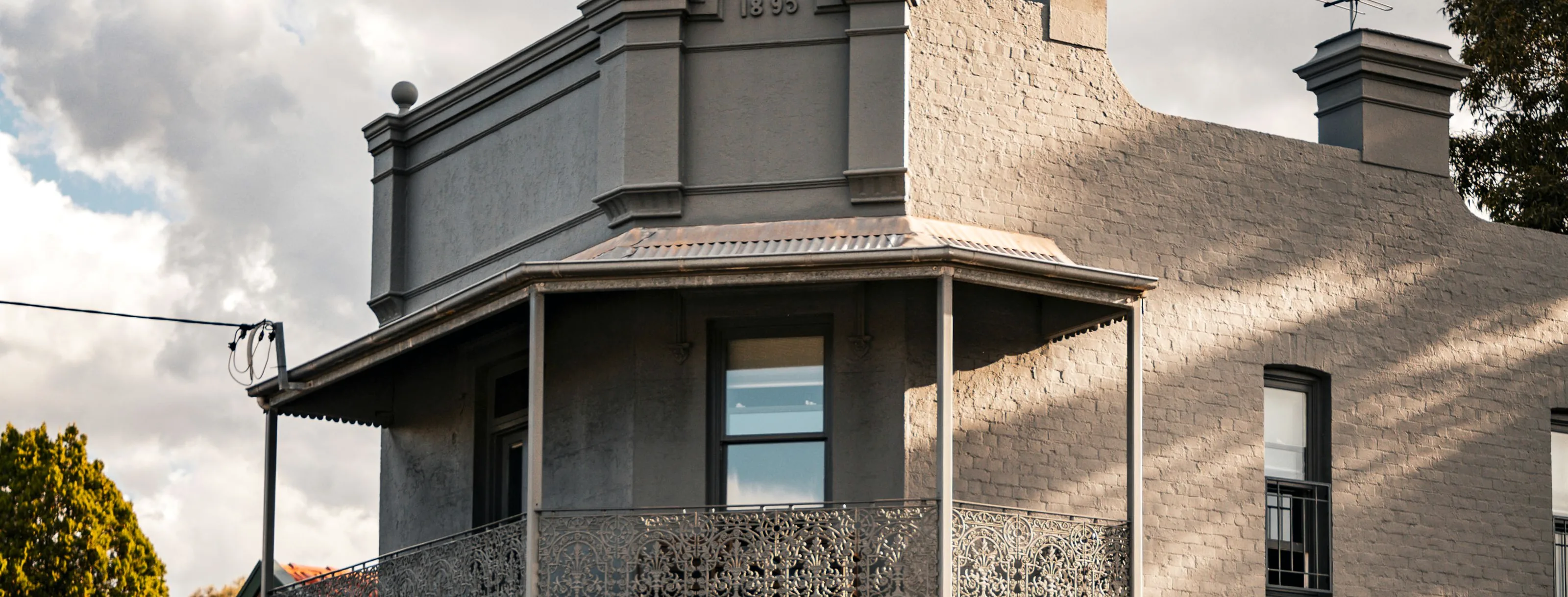 Victorian corner building in inner Sydney with iron lace, parapet and brick chimneys