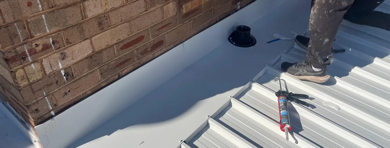 Metal deck roof meeting a brick parapet wall