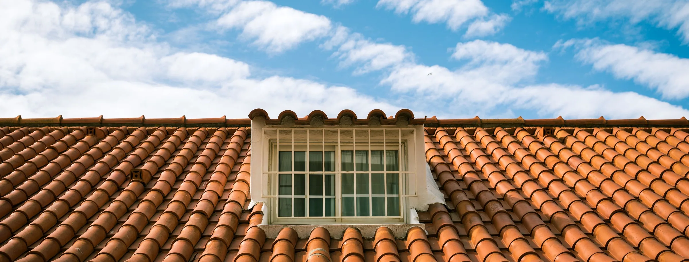 Skylight set into a terracotta tiled roof against a blue sky