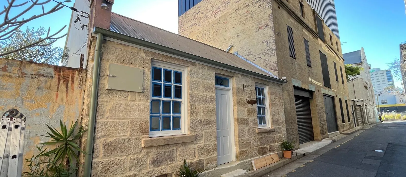 Sandstone heritage cottage on a Sydney CBD laneway beneath a modern tower