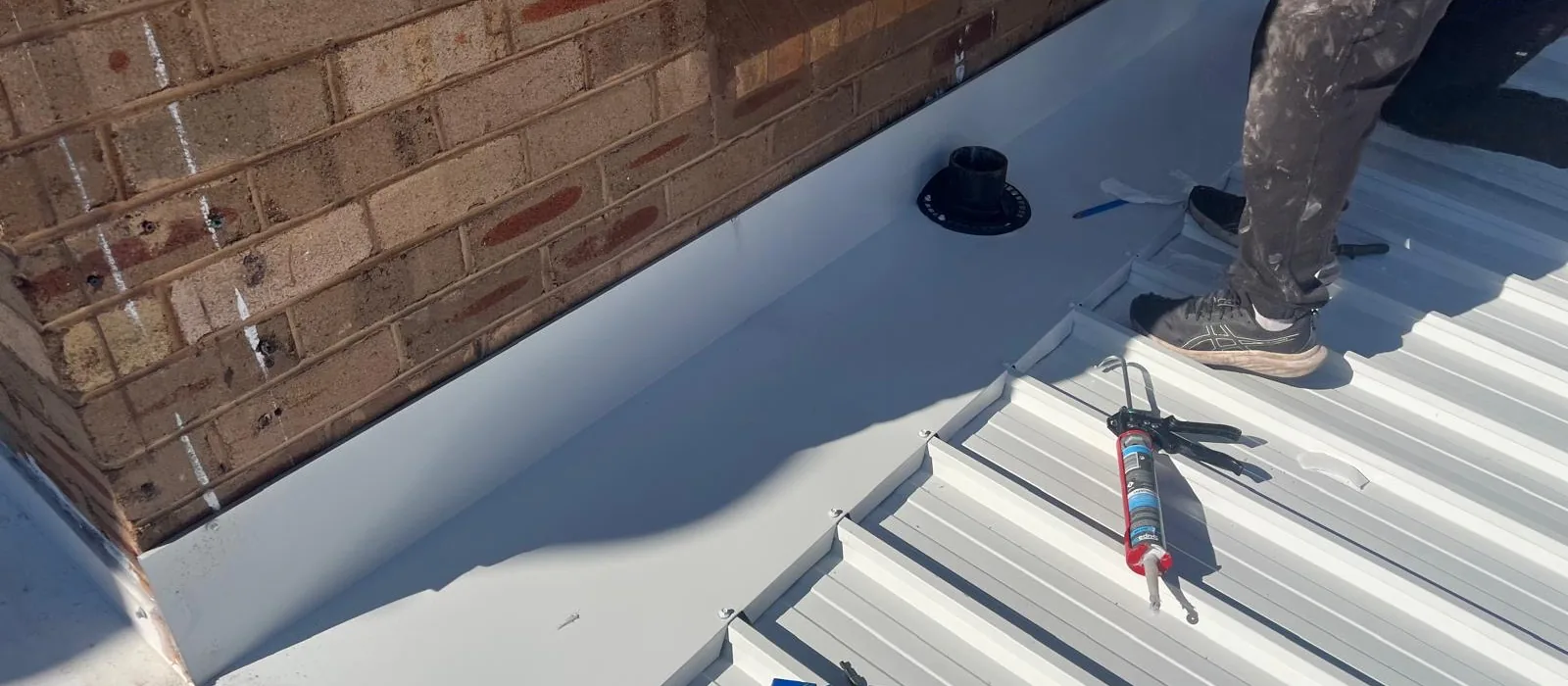 Metal deck roof meeting a brick parapet wall
