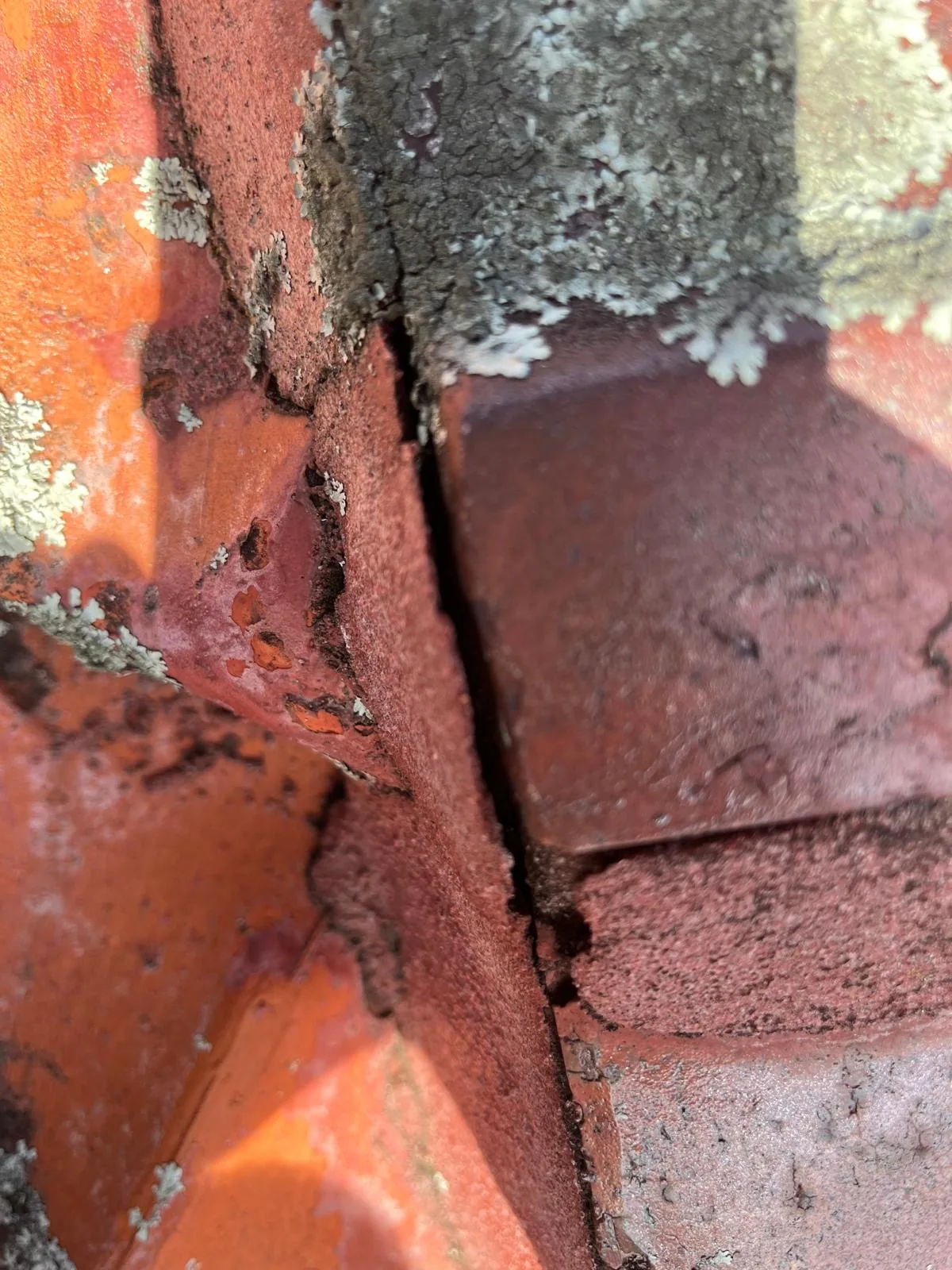 Cracked ridge capping with perished mortar on a terracotta tile roof
