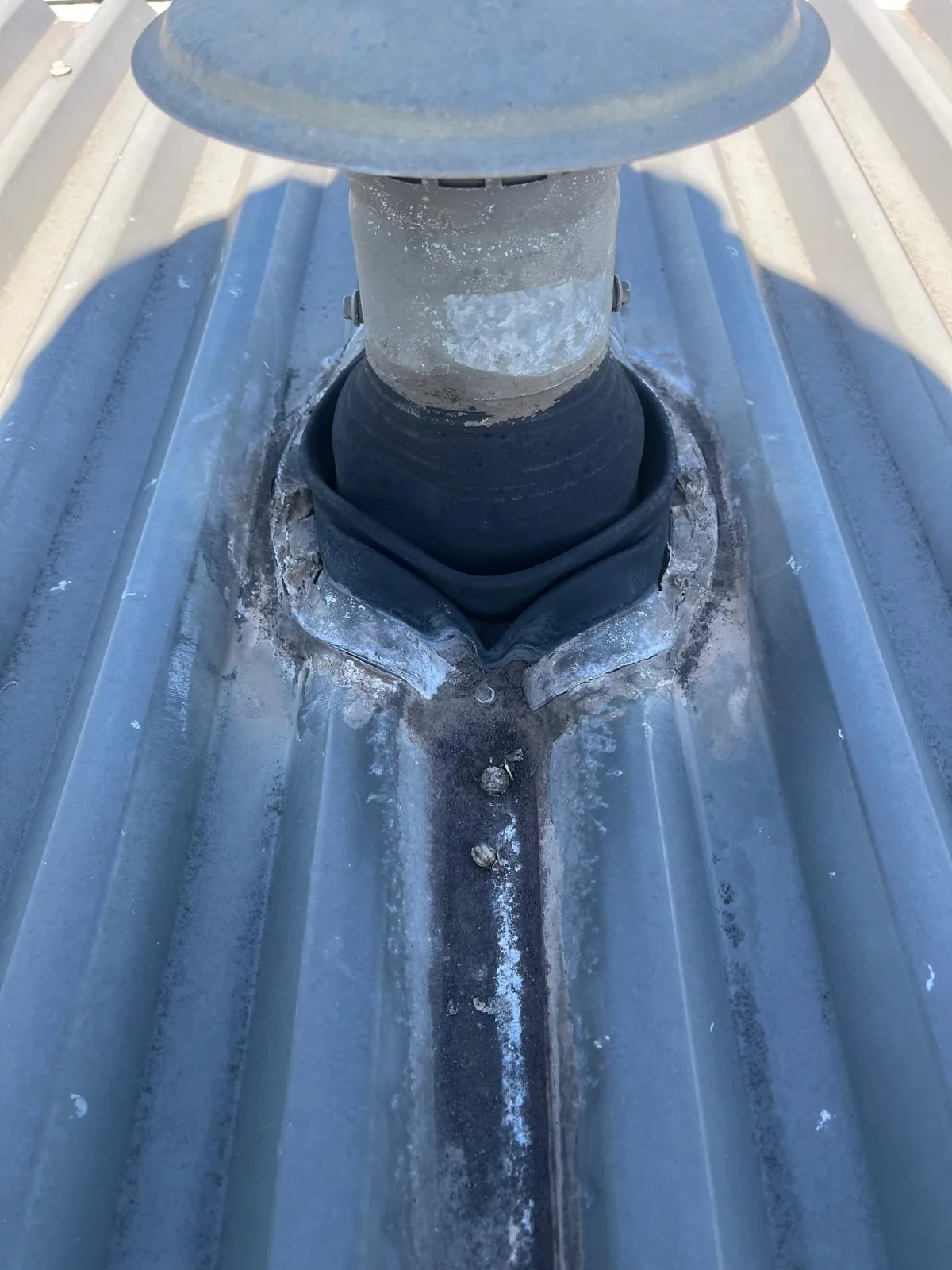 Roof vent penetration sealed with a rubber boot and sealant