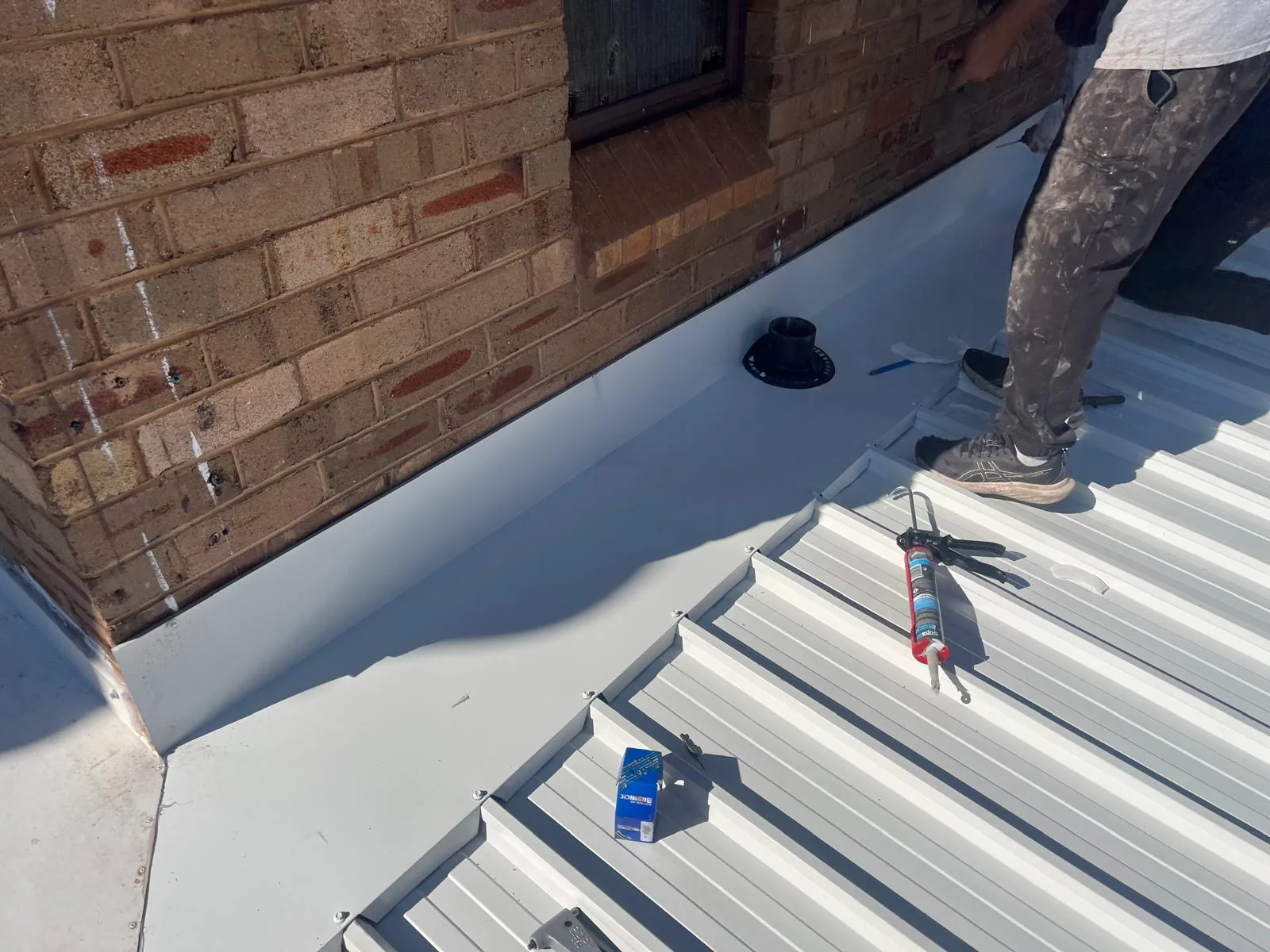 Metal deck roof meeting a brick parapet wall